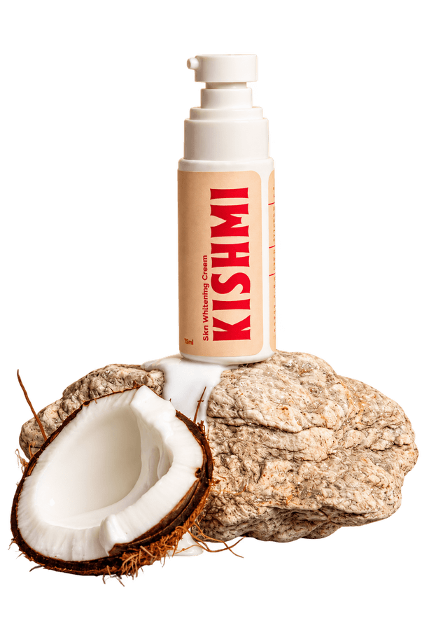 Kishmi cream bottle on a rock beside a halved coconut